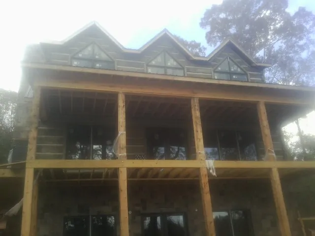Dormers and porch framing on a large log home under construction — Roof Coating work by our crew in Custar