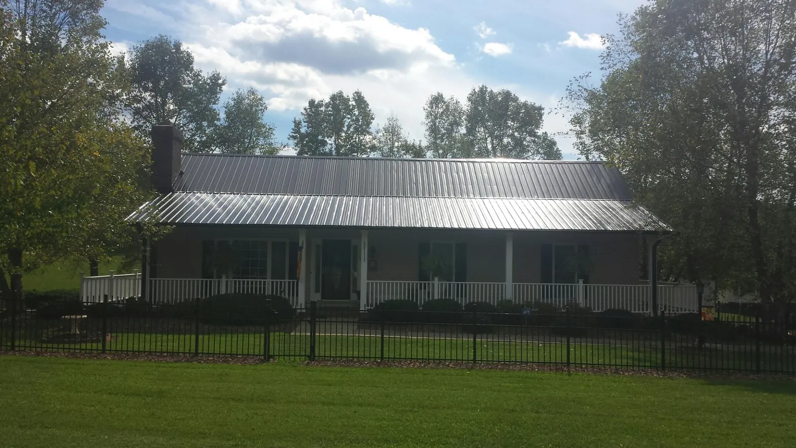 Gray metal roof on a brick ranch with a full width front porch — Gutter Guard Installation work by our crew in Custar