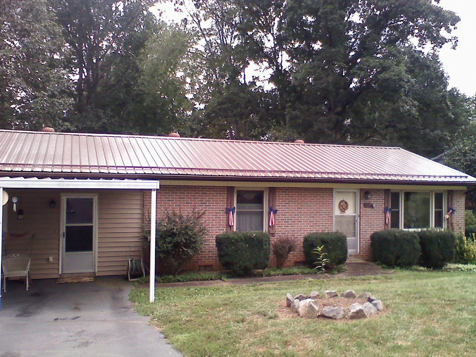 Bronze metal roof and carport on a brick ranch home — Roof Repair work by our crew in Custar
