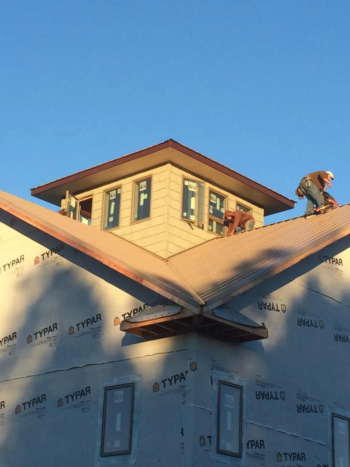 Roofers working around a rooftop cupola on a new metal roof at sunset — Roof Waterproofing in Custar by Roofing Brothers
